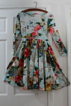 a dress hanging on a door handle in front of a white door with floral print