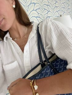 a woman wearing a white shirt and holding a blue purse