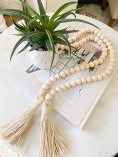 a wooden beaded necklace on a table next to a potted plant