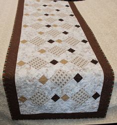 a quilted table runner with brown and white squares on the edges, along with a black border