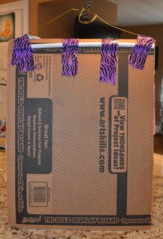 an open box with purple ribbon on it sitting on a counter top next to a microwave