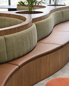 a curved bench with plants in the center and an orange rug on the floor next to it