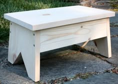 a small wooden table sitting on top of a cement ground next to some green grass