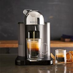 an espresso machine with coffee being poured into it and cookies on the side