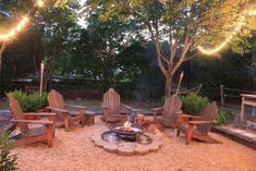 an outdoor fire pit surrounded by chairs and lights