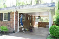 a man standing on a ladder in front of a brick house with the door open