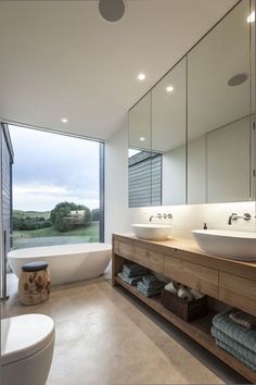 a bathroom with two sinks and a bathtub in front of a large glass window