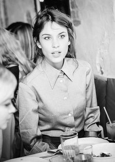 a black and white photo of a woman sitting at a table