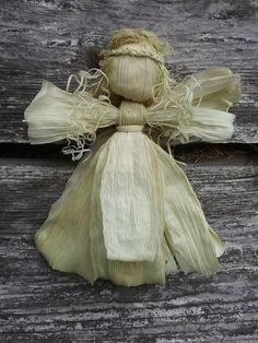 an old doll made out of corn on the cob is sitting on a wooden surface