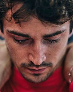 a close up of a man with his hands on his shoulder looking down at something