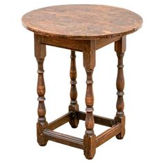 an old wooden table with turned legs and a round top, isolated against a white background