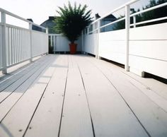 a wooden deck with white railing and planter