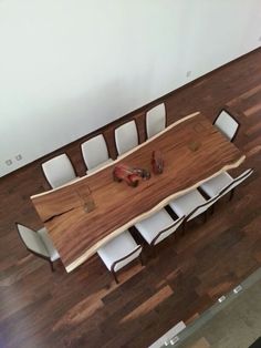 a wooden table with white chairs and a pair of red shoes on the floor next to it