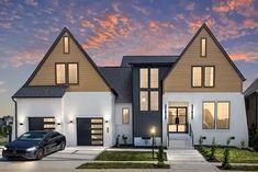 a car is parked in front of a two story house at night with lights on