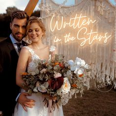 a man and woman standing next to each other in front of a neon sign that says written in the stars