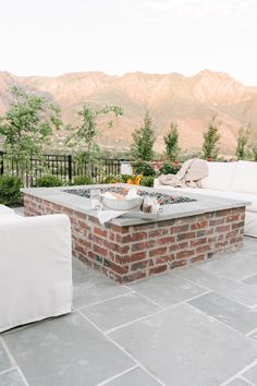 an outdoor fire pit surrounded by furniture and mountains in the backgrouf area