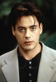 a man in a white jacket and black shirt looking at the camera with an intense look on his face