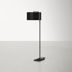 a floor lamp with a black shade on the base and a white wall in the background