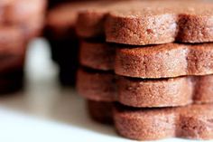 a stack of brown sugar cookies sitting on top of a white counter next to cupcakes