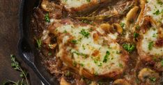 a skillet filled with meat covered in sauce and mushrooms, garnished with parsley