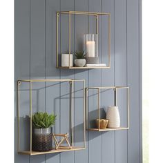 two gold metal shelves with plants and candles on them against a blue wall in a living room