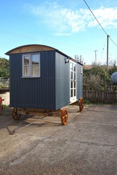 a tiny house sitting on wheels in the middle of a lot with a sky background