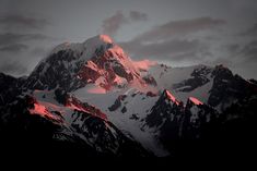 the mountain is covered in snow and red light from the sun shining down on it