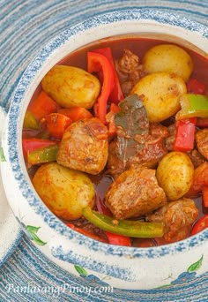 a bowl filled with meat and vegetables on top of a blue and white table cloth