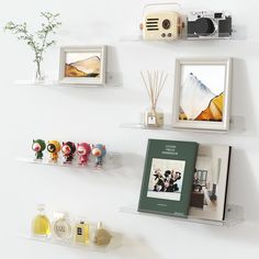 there are three shelves with pictures and other items on them, along with two books