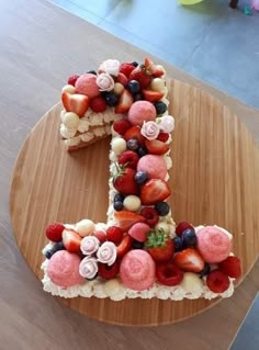 a cake shaped like the number one made out of fruit on top of a wooden table