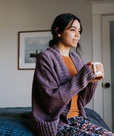 a woman sitting on a couch holding a remote control in her hand and looking off into the distance