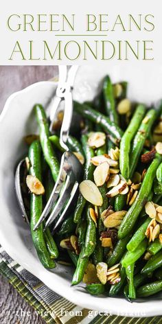 a white bowl filled with green beans and almonds on top of a table cloth