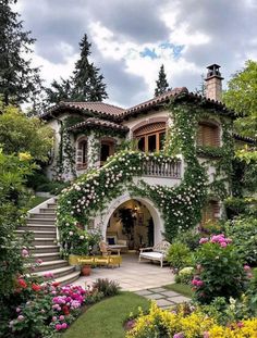 a house covered in vines and flowers with stairs leading up to it