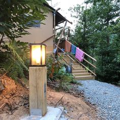 a light that is on some kind of pole in the dirt near stairs and trees