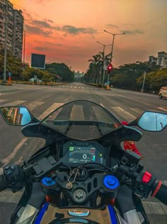 a motorcycle is parked on the side of the road with its lights on at sunset