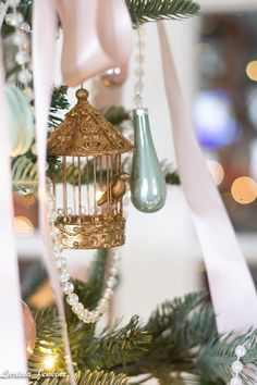 an ornament hanging from a christmas tree with ribbons and lights in the background