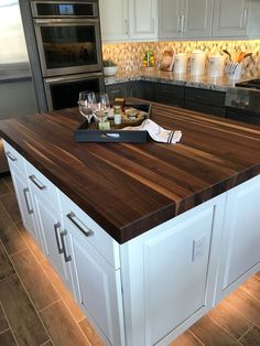 a kitchen island with two wine glasses on it and some food in front of the counter