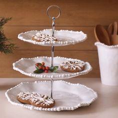 three tiered trays with cookies on them and holly berries in the center, along with utensils