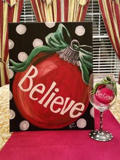 a wine glass sitting on top of a table next to a sign that says believe