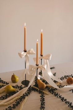 a table topped with candles and fruit on top of a white cloth covered tablecloth