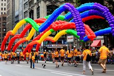 a group of people walking down a street with giant balloons