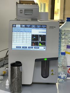 a machine that is sitting on top of a table next to water bottles and cans