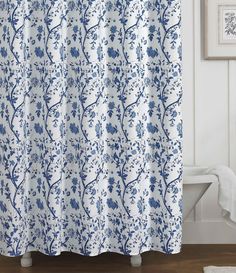 a shower curtain with blue and white flowers on it in a bathroom next to a bathtub