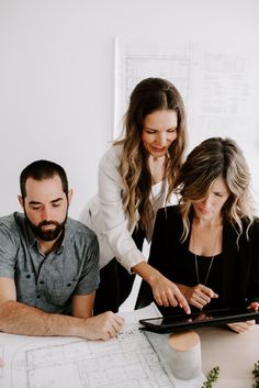 two women and a man looking at something on a tablet