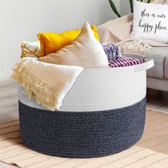 a large round basket with pillows and blankets on it in front of a couch area