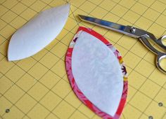 a pair of scissors sitting on top of a cutting board next to a piece of paper