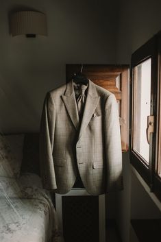 a suit and tie hanging on a clothes hanger in a room next to a bed