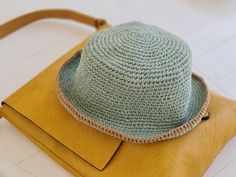 a crocheted hat sitting on top of a yellow purse