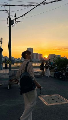 a man is walking down the street with his back to the camera as the sun sets