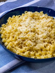 a blue bowl filled with macaroni and cheese on top of a table cloth